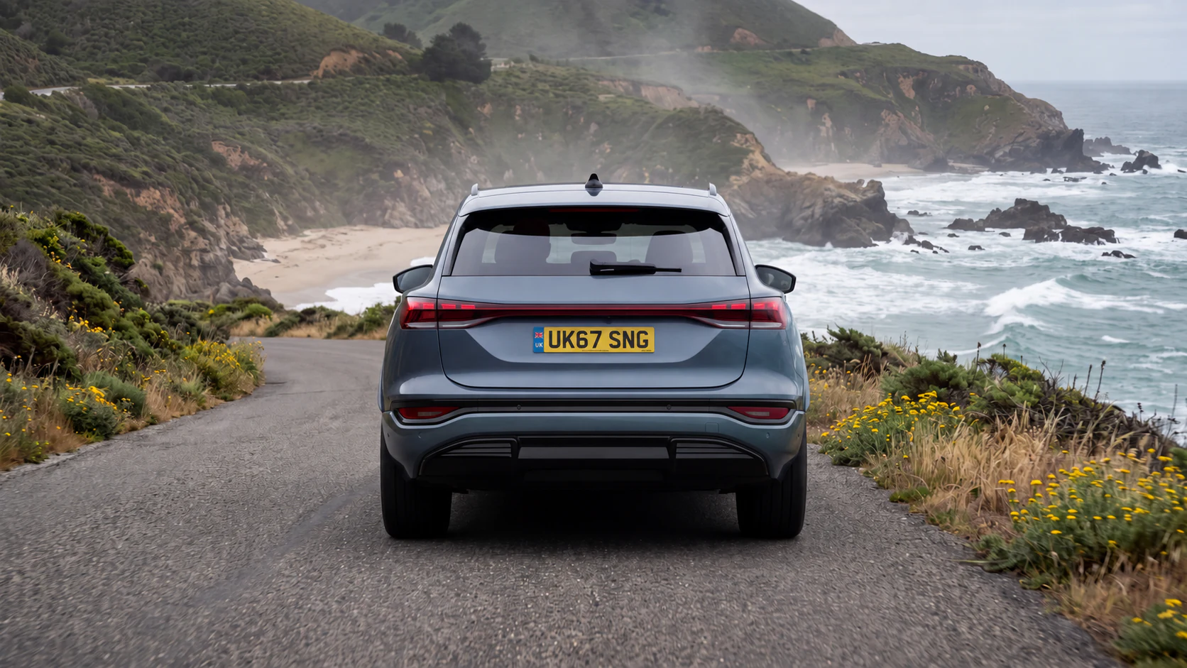 Grey SUV seen straight from behind on a coastal road above the sea